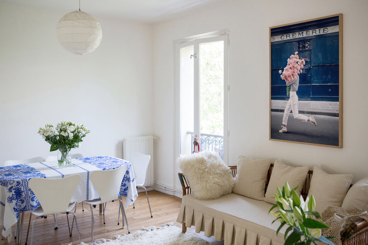 Follow Your Bliss is an image of a girl with a huge bouquet of pink carnations in her arms skipping along the street in front of La Crèmerie in the 6th Arrondissement in Paris.