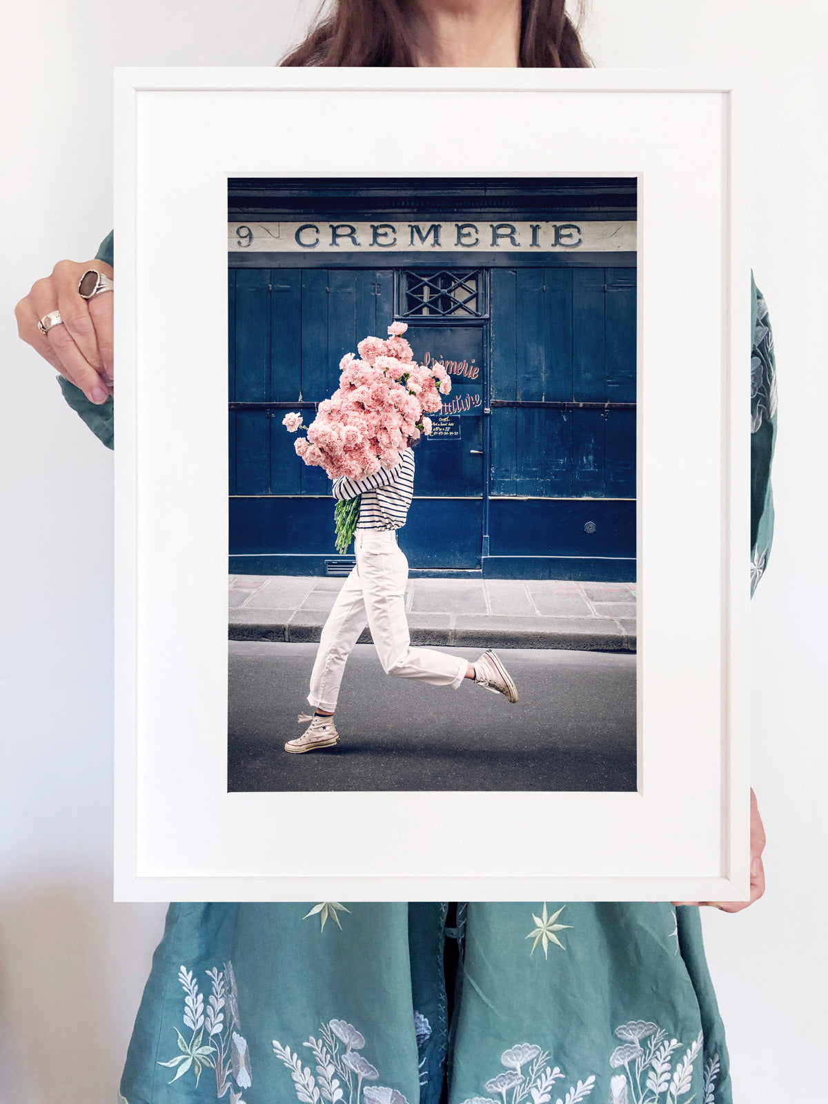 Follow Your Bliss is an image of a girl with a huge bouquet of pink carnations in her arms skipping along the street in front of La Crèmerie in the 6th Arrondissement in Paris.